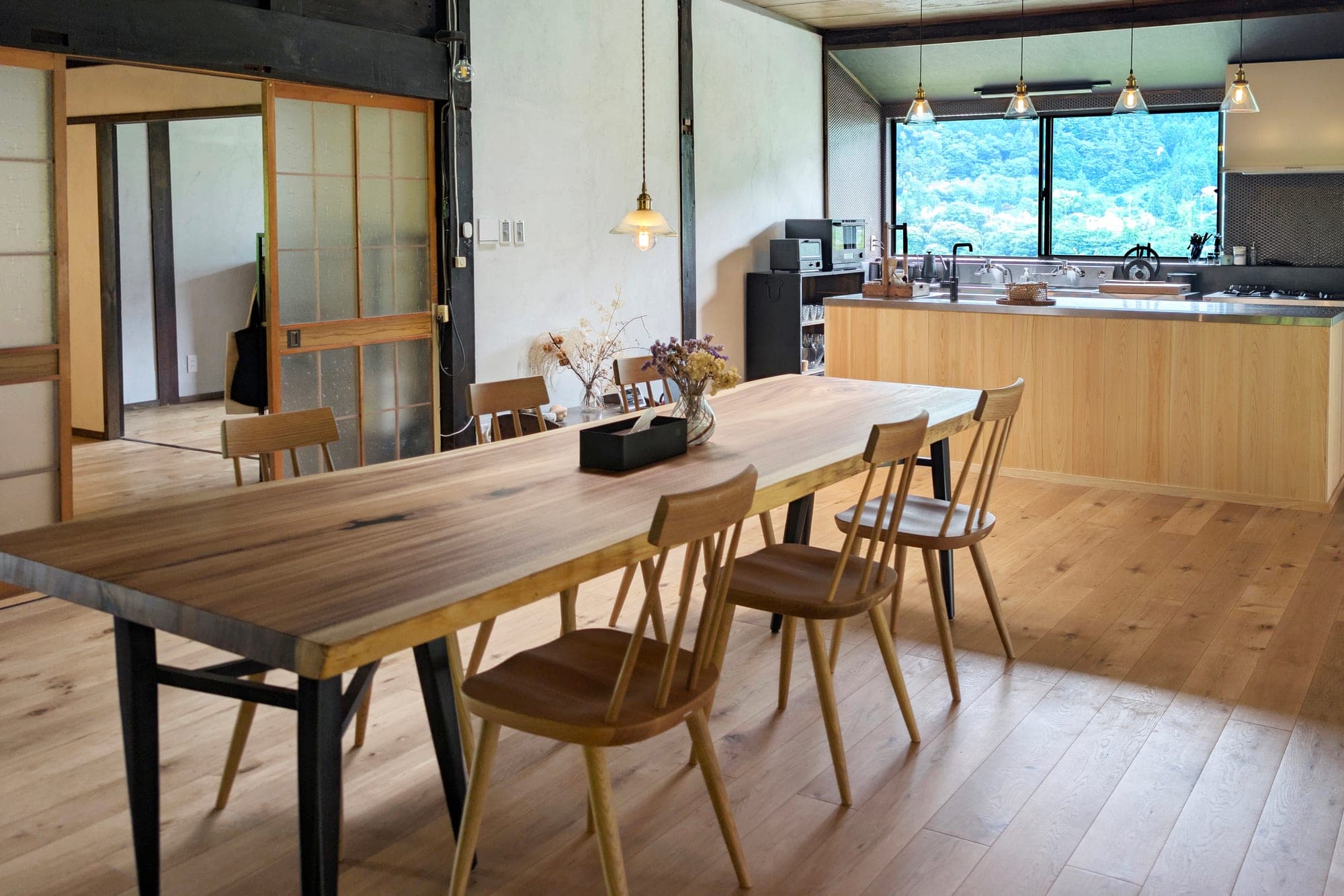 KinoMa dining and kitchen area with a live-edge wooden table, wooden chairs, and mountain views through the window