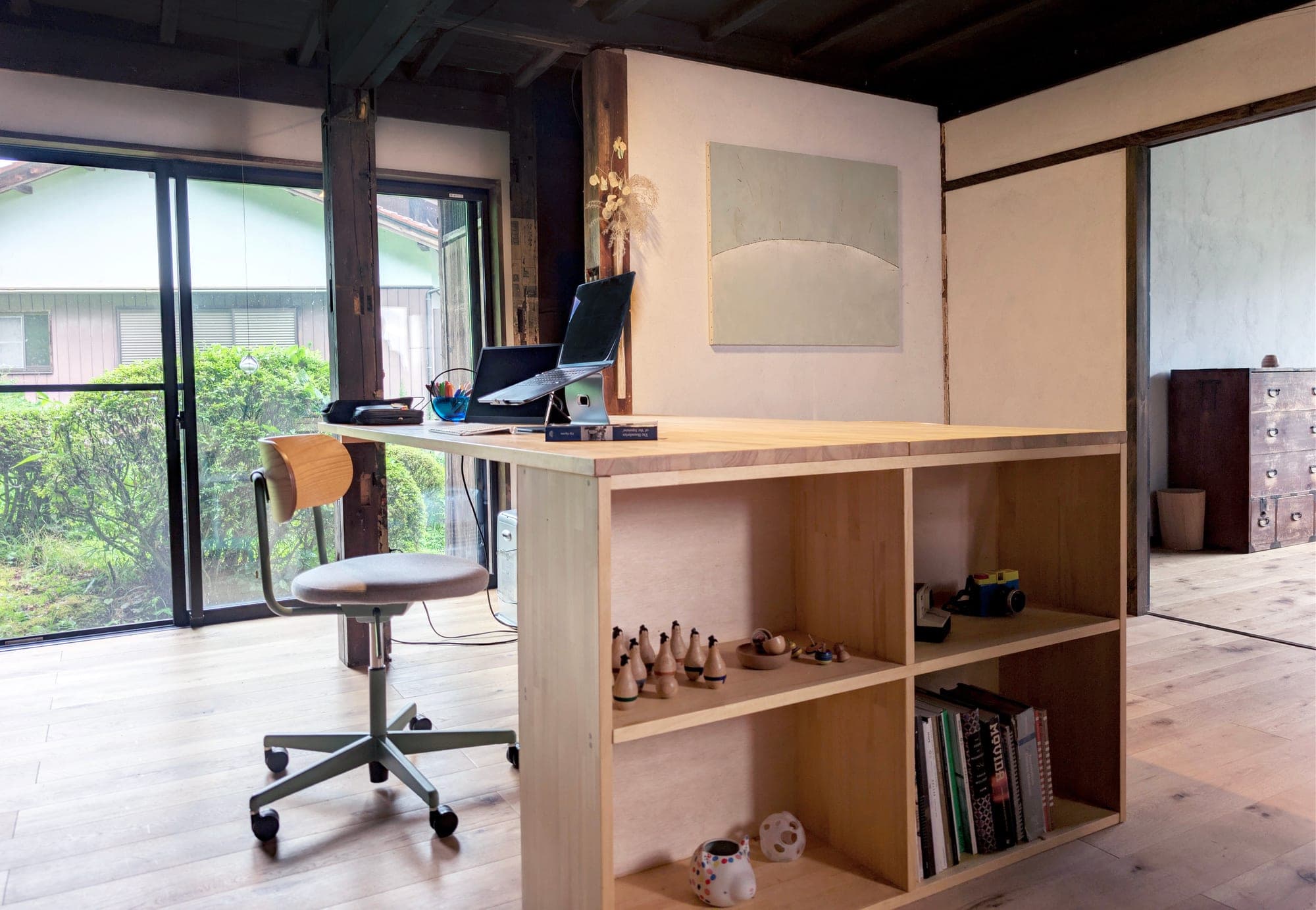 Home office with a wooden desk, shelving, and garden views through large windows