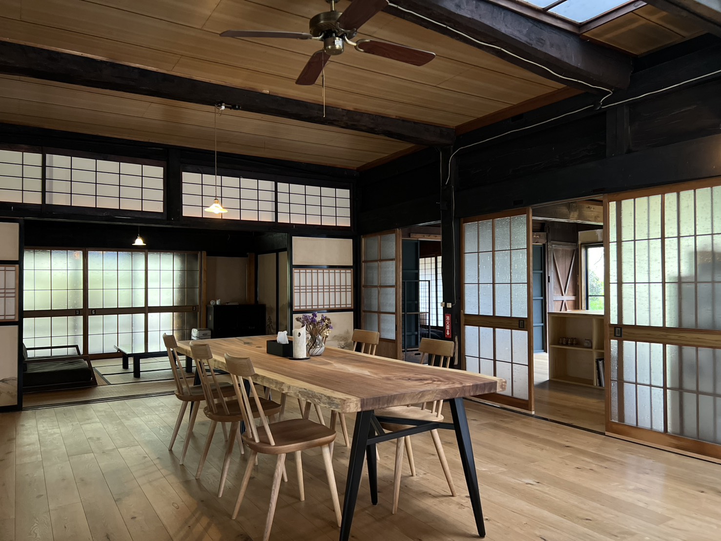 KinoMa traditional kominka interior with live-edge dining table, shoji screens, and exposed wooden beams