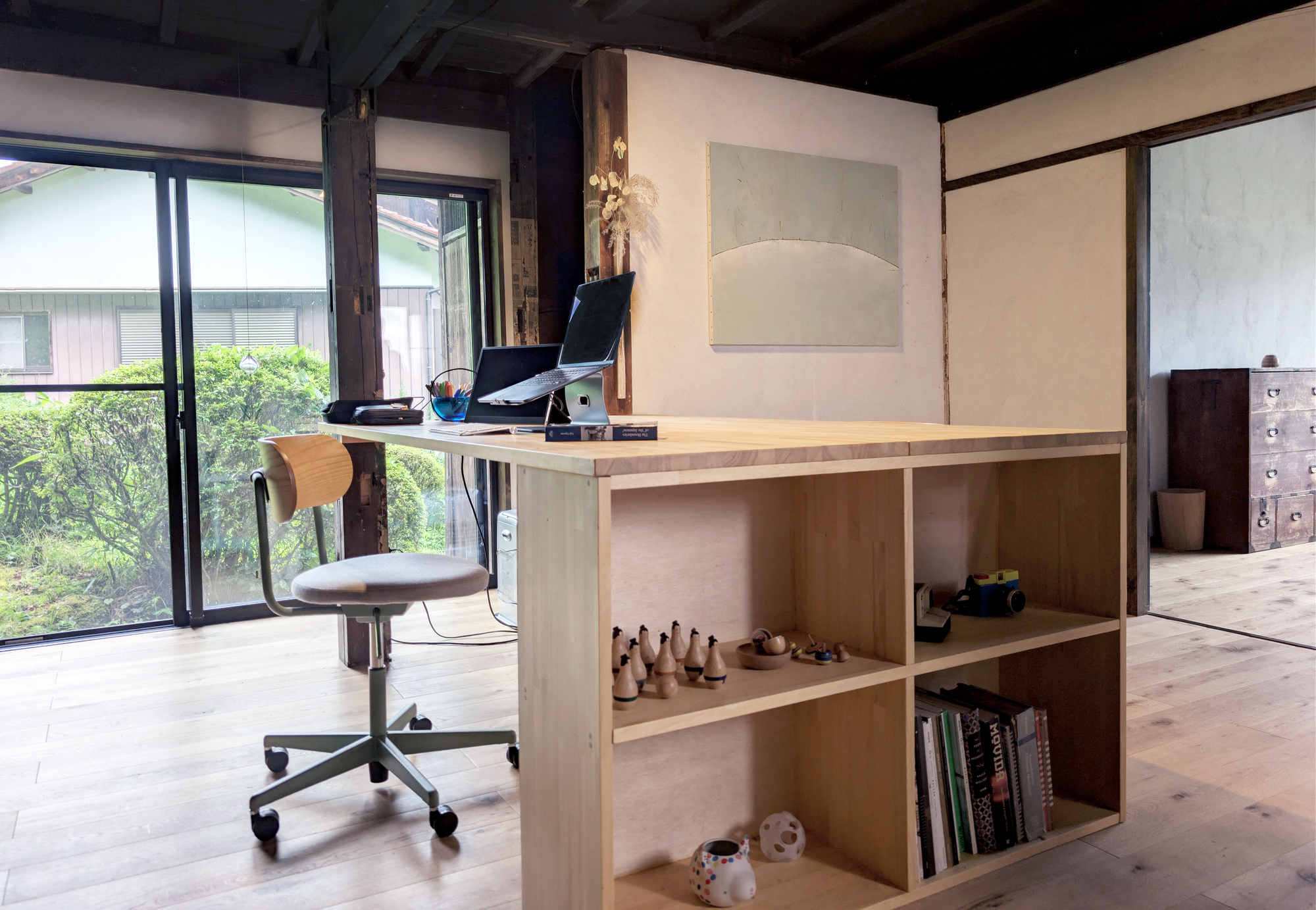 Home office with a wooden desk, shelving, and garden views through large windows