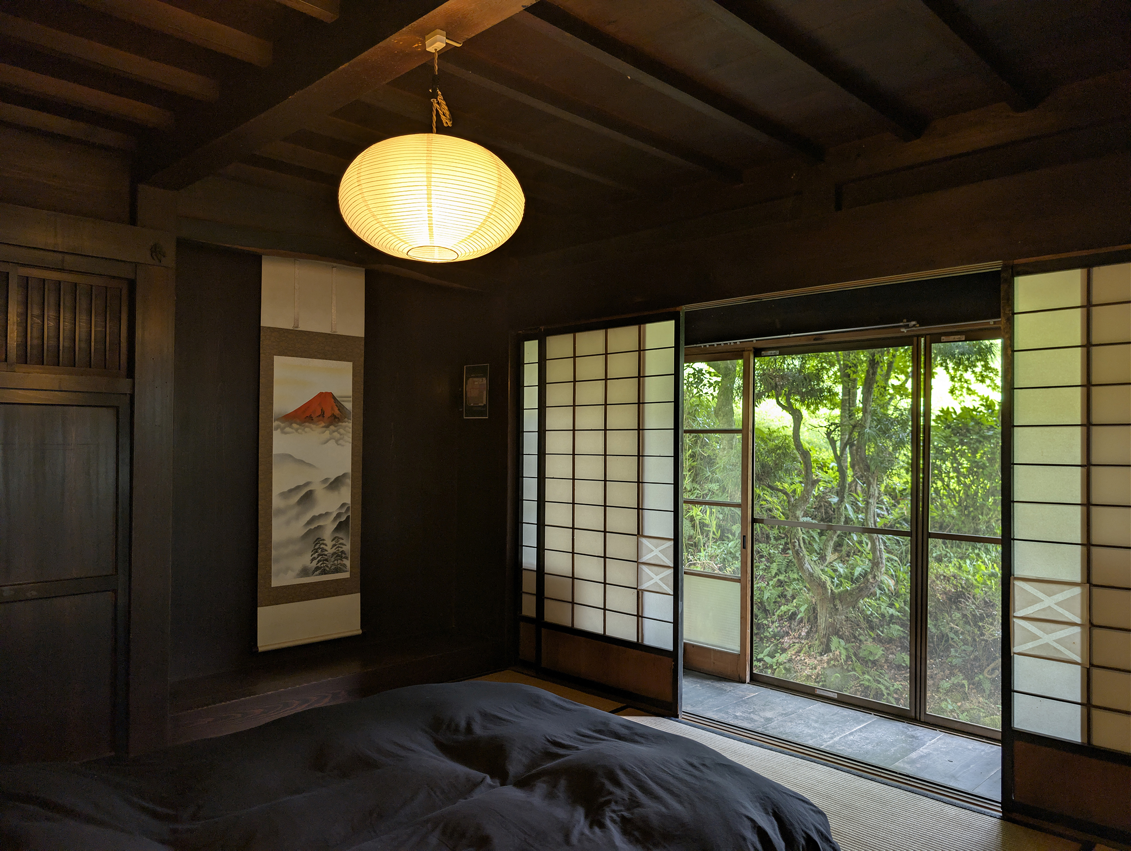 Tatami room with a paper lantern, hanging scroll, and shoji screens opening to the garden